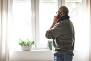 Older adult man working at home taking a phone call.