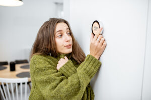 Why Is My Heat Pump Turning On and Off Frequently? A woman turning up her heat.