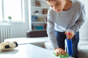 boy cleaning table in his home.