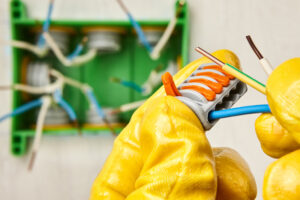 Cable or wire connector terminal block with spring lever for connecting electrical conductor. An electrician installs a junction box in an office building.