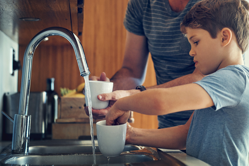 Shot of a father and son washing dishes together at home.